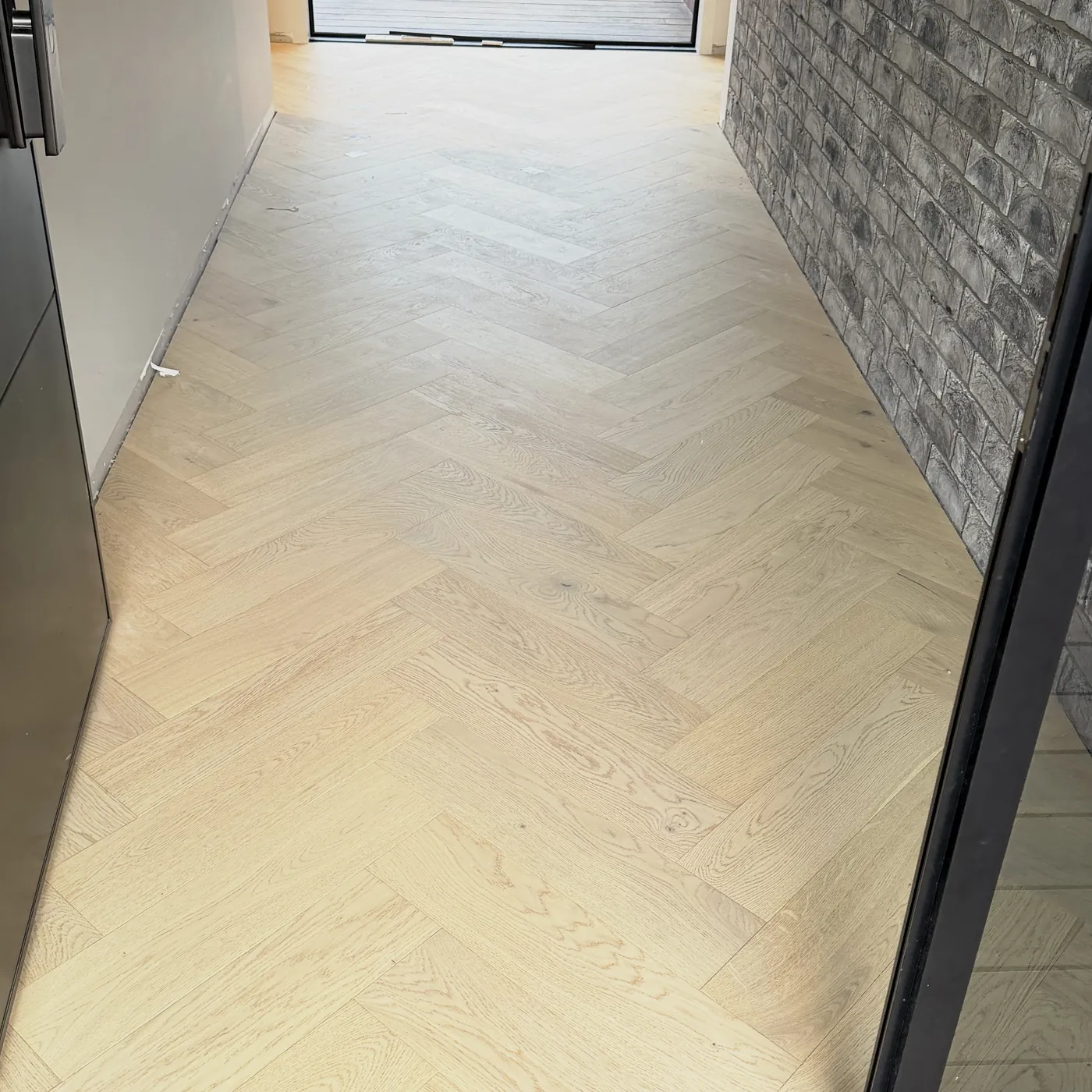 Whitewashed herringbone floor beside a brick wall