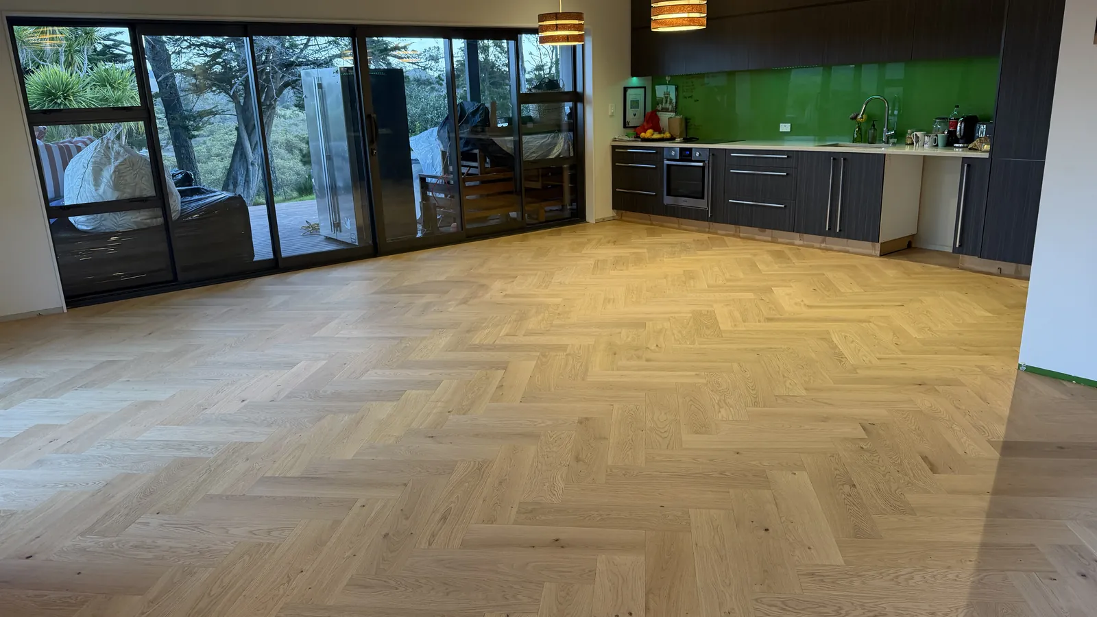 Natural Clear herringbone engineered timber through an open plan kitchen and living space at Whangaparaoa Road, Red Beach