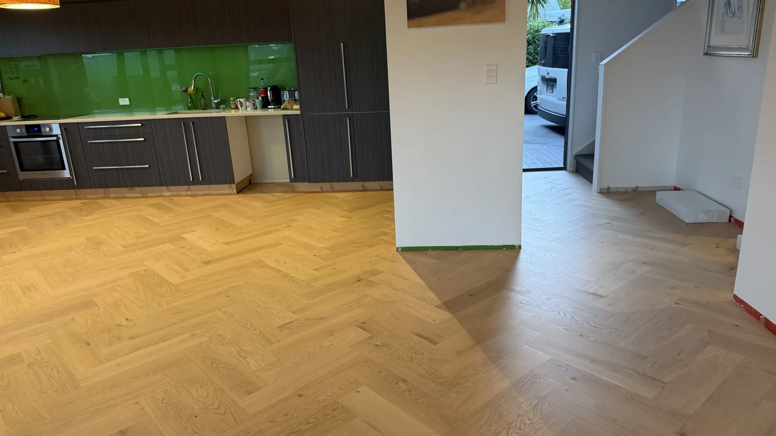 Natural Clear herringbone engineered timber running from the kitchen to the entry at Whangaparaoa Road, Red Beach