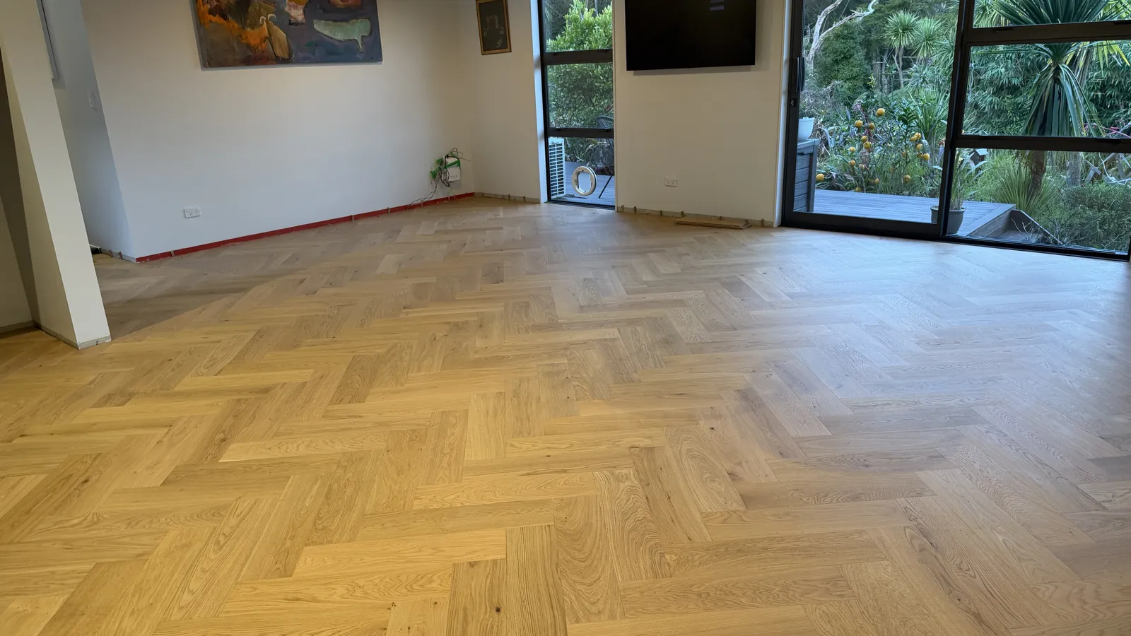 Natural Clear herringbone engineered timber in a living room in evening light at Whangaparaoa Road, Red Beach
