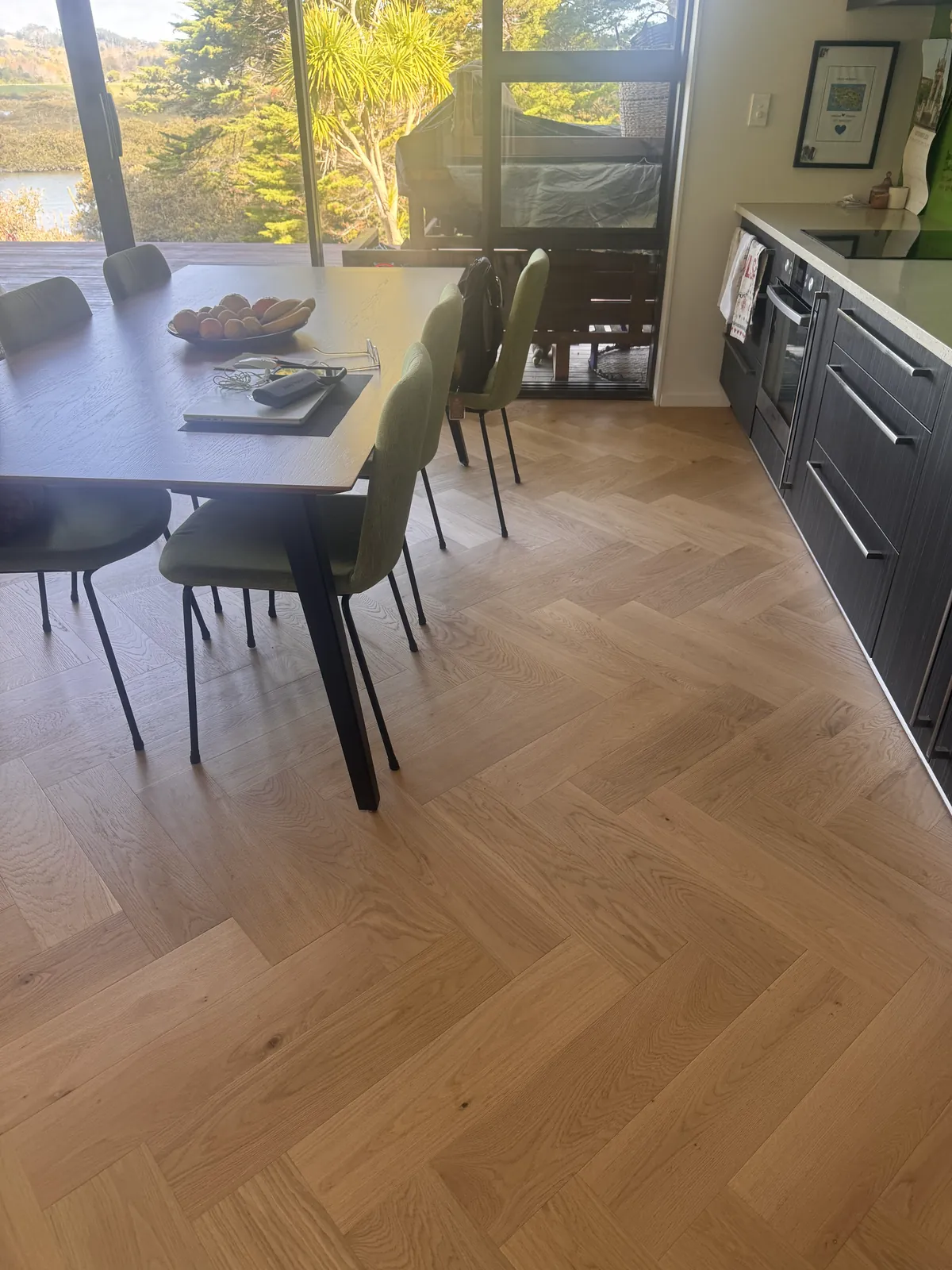 Natural Clear herringbone engineered timber under the dining table in morning sun at Whangaparaoa Road, Red Beach
