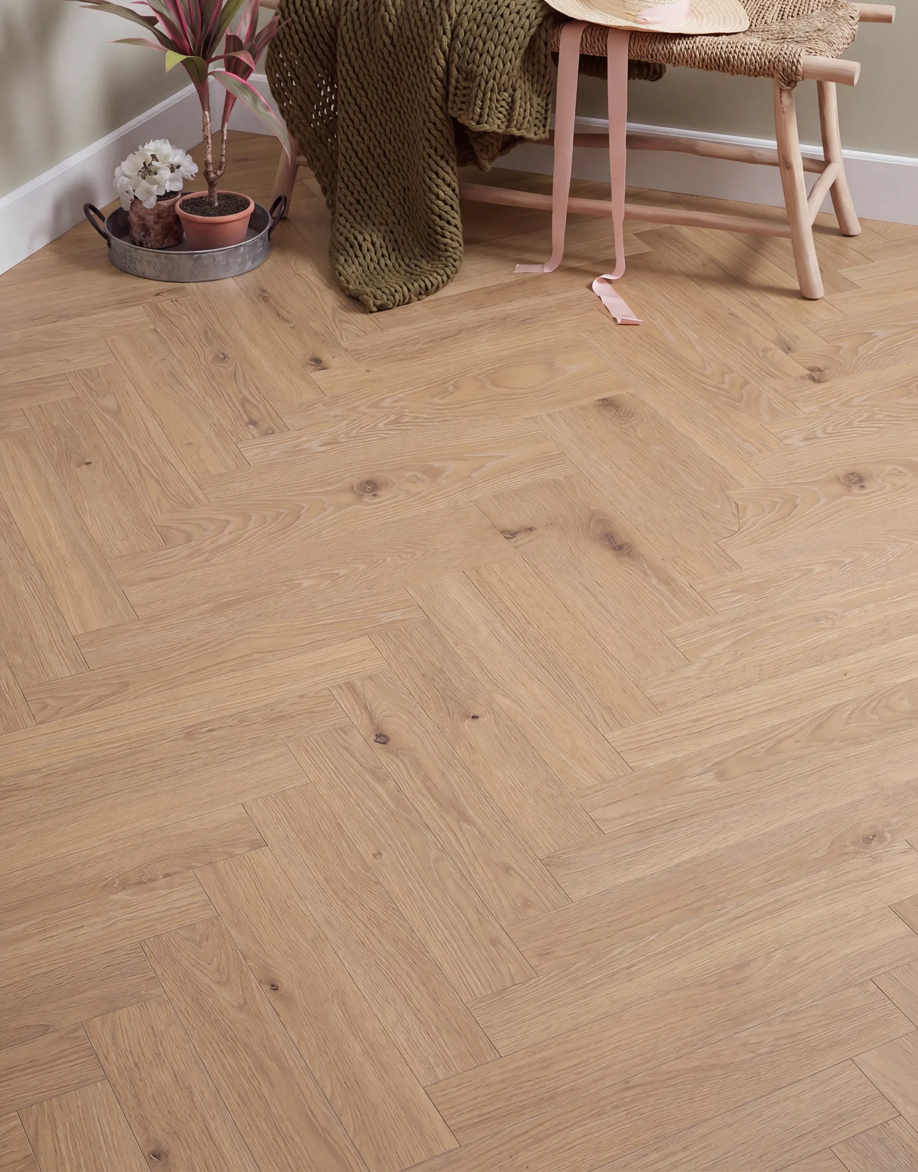 Smouldered herringbone engineered timber in a styled corner with a woven bench