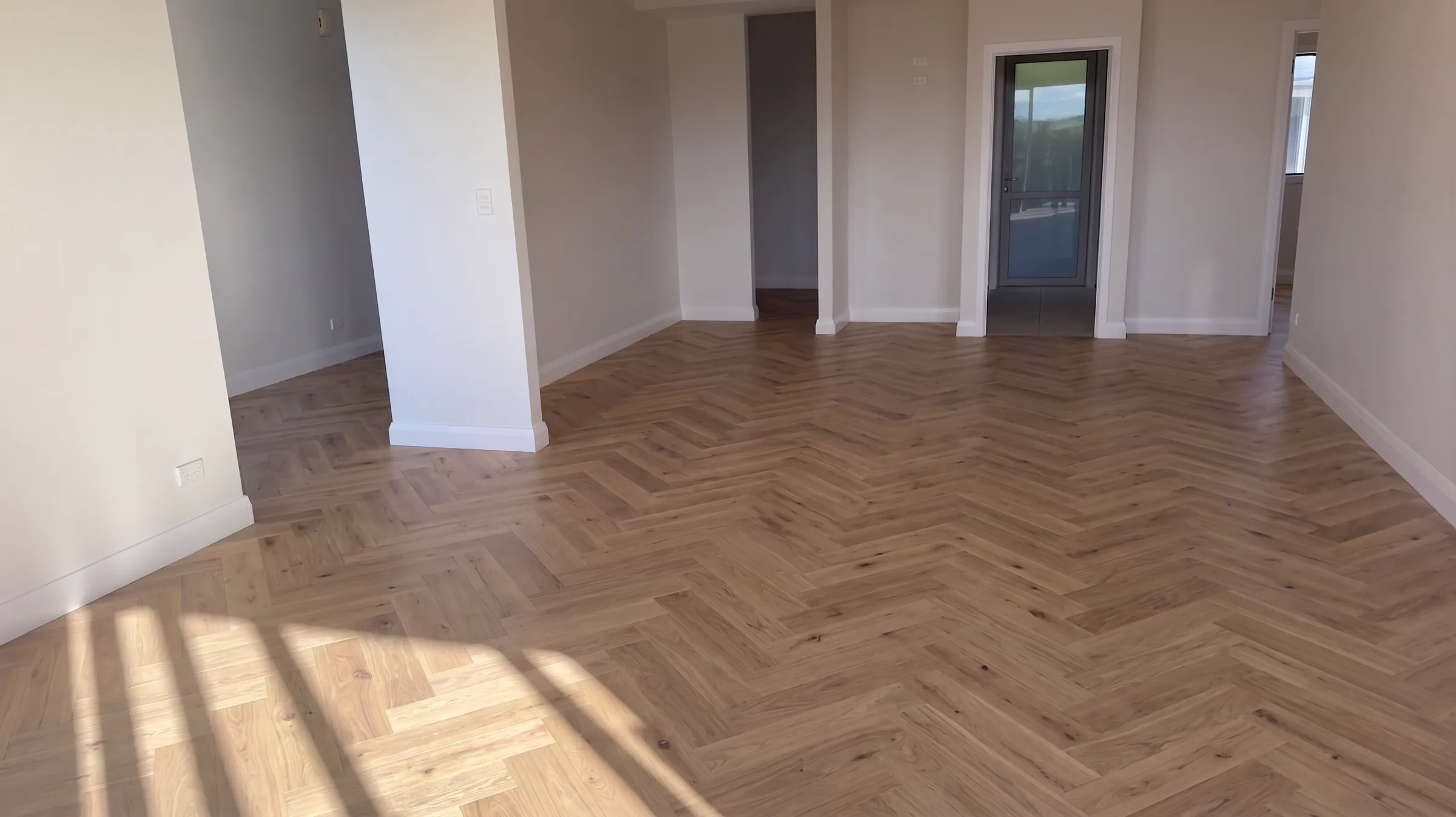 West herringbone engineered timber through a soon to be furnished living room and hallway