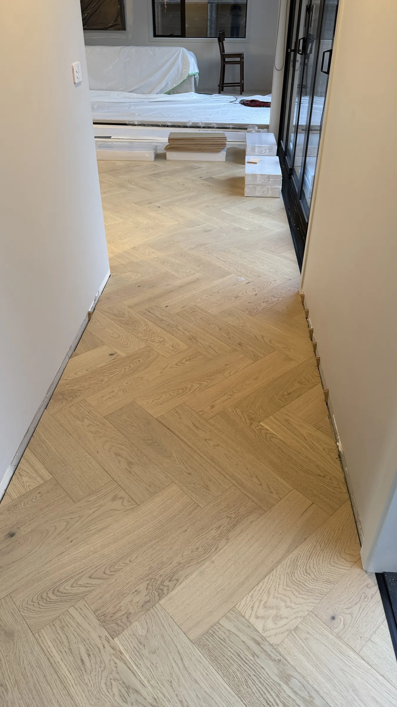Western herringbone engineered timber down the hallway at Whitford Park Road, Whitford, packs still landing