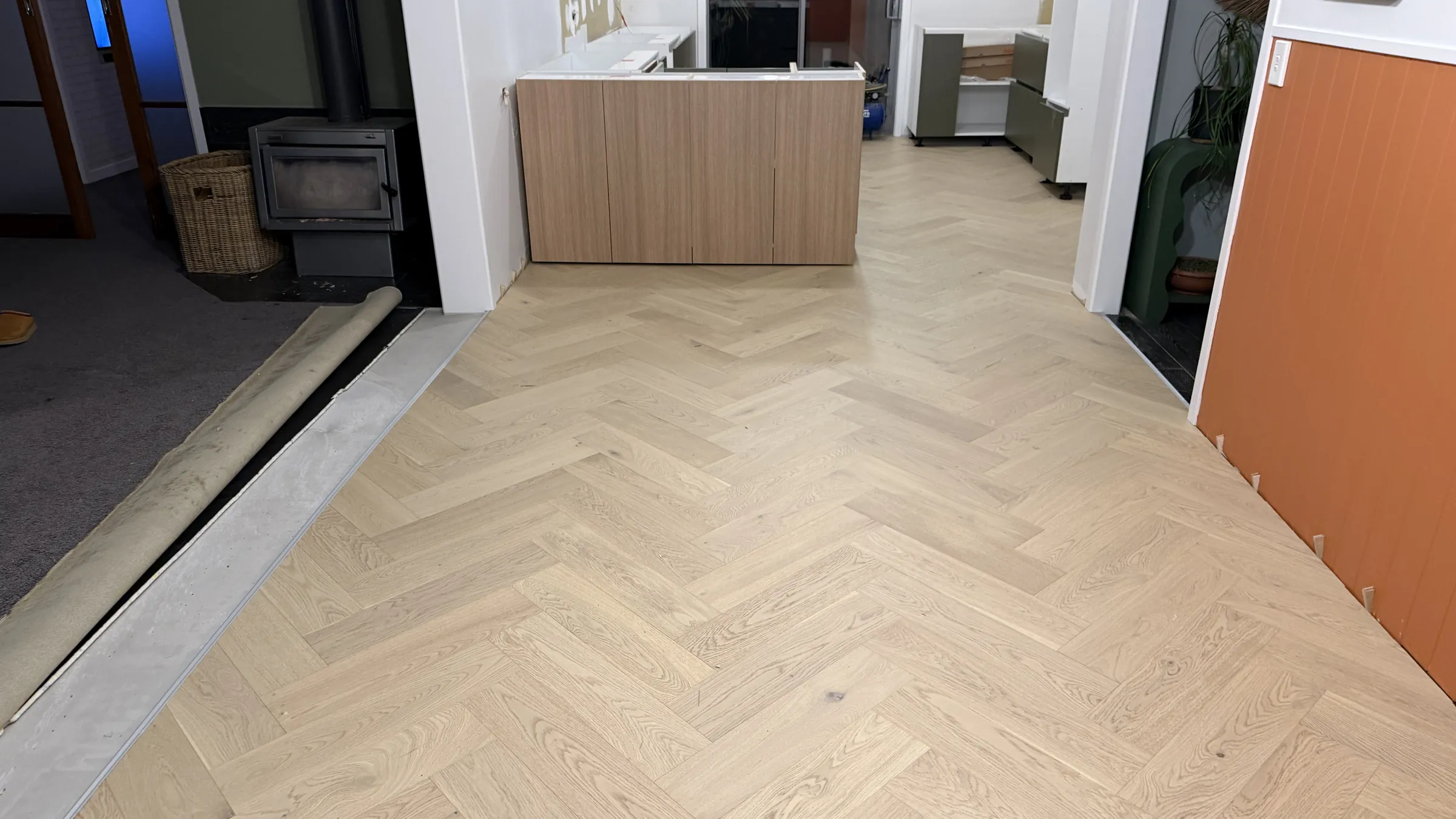 Western herringbone engineered timber through the fireplace room mid install at Shaw Road, Oratia