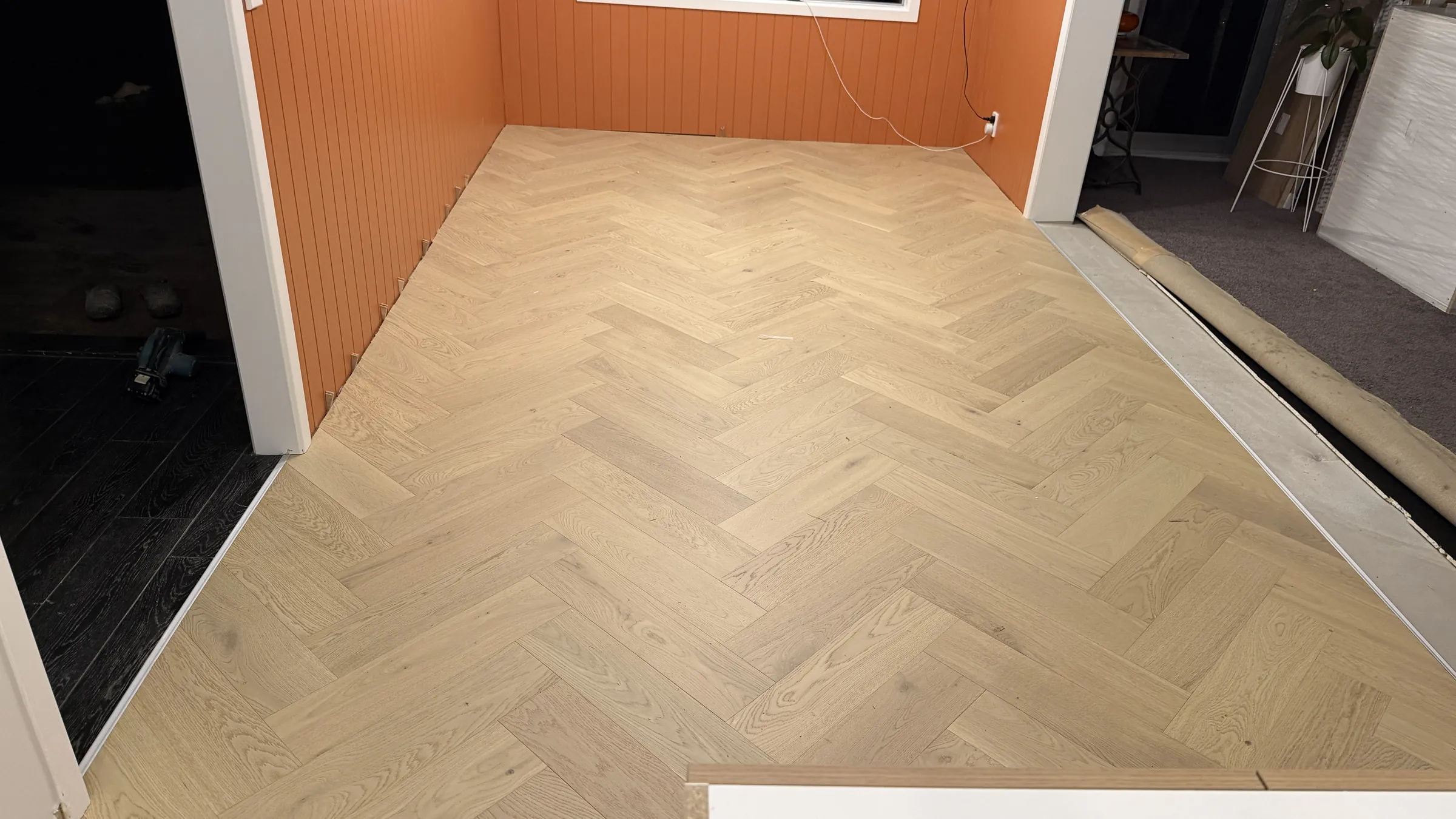 Western herringbone engineered timber in the orange panelled room at Shaw Road, Oratia, laid by evening