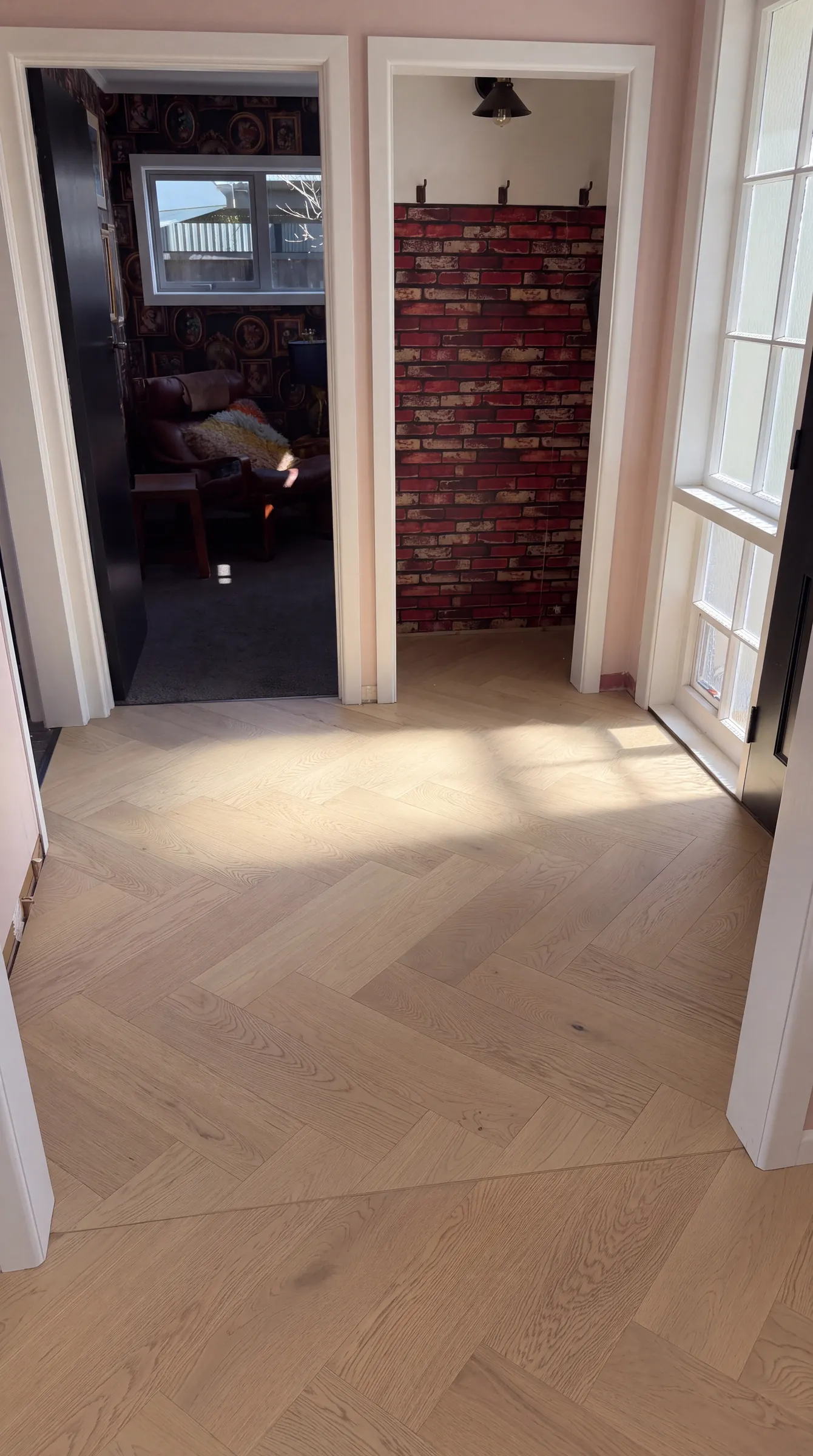 Western herringbone engineered timber in the sunlit entry at Shaw Road, Oratia, laid on the return visit