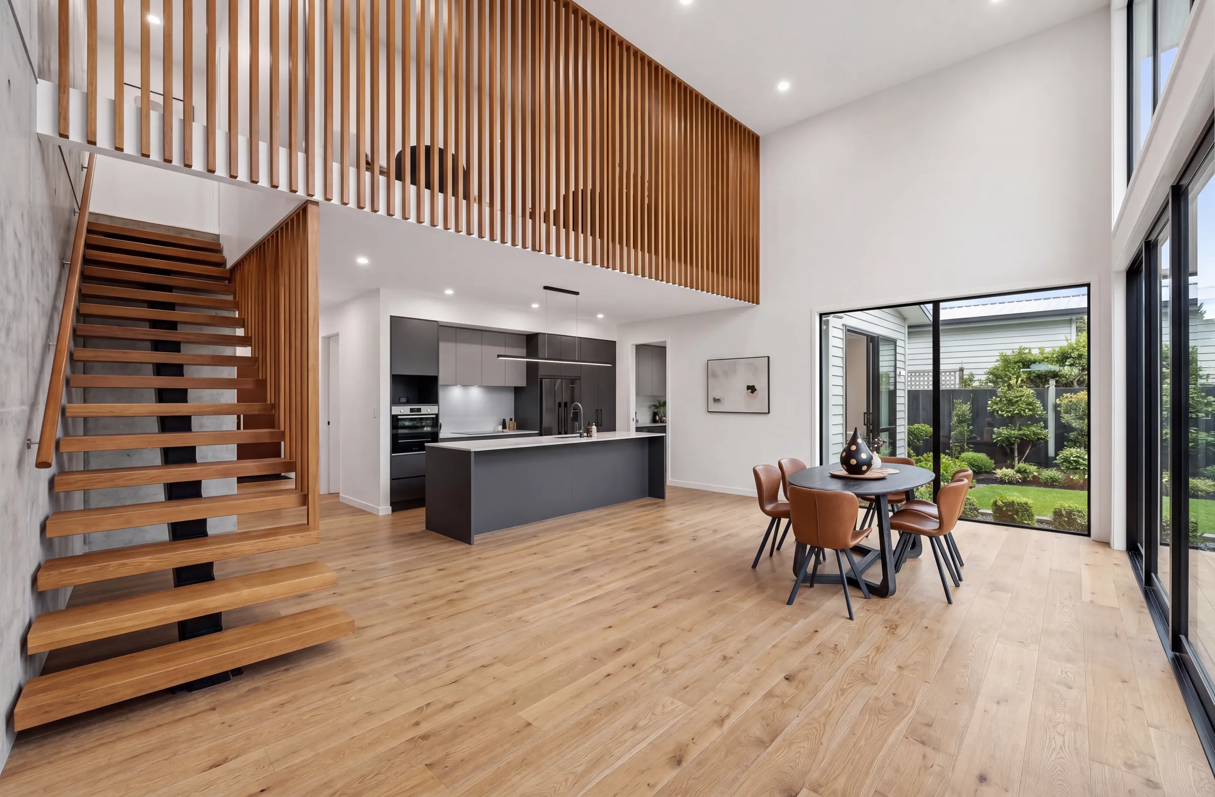 Smouldered oak plank through a double-height living space with a floating timber stair and slat screen