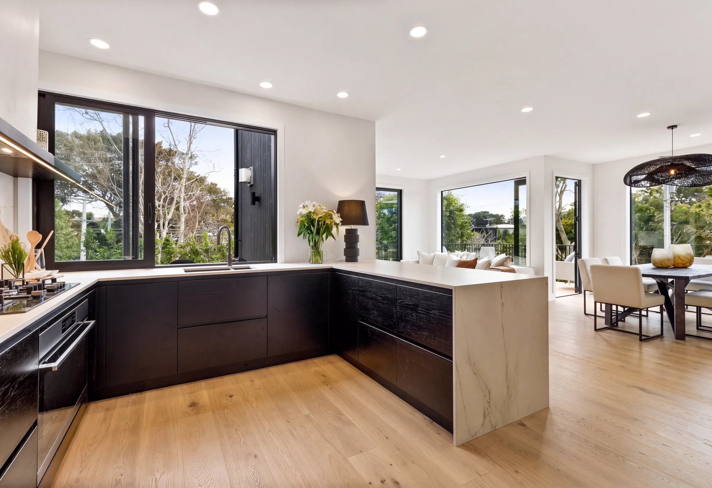 Western oak plank across an open-plan kitchen and living room at Domain Crescent, Muriwai