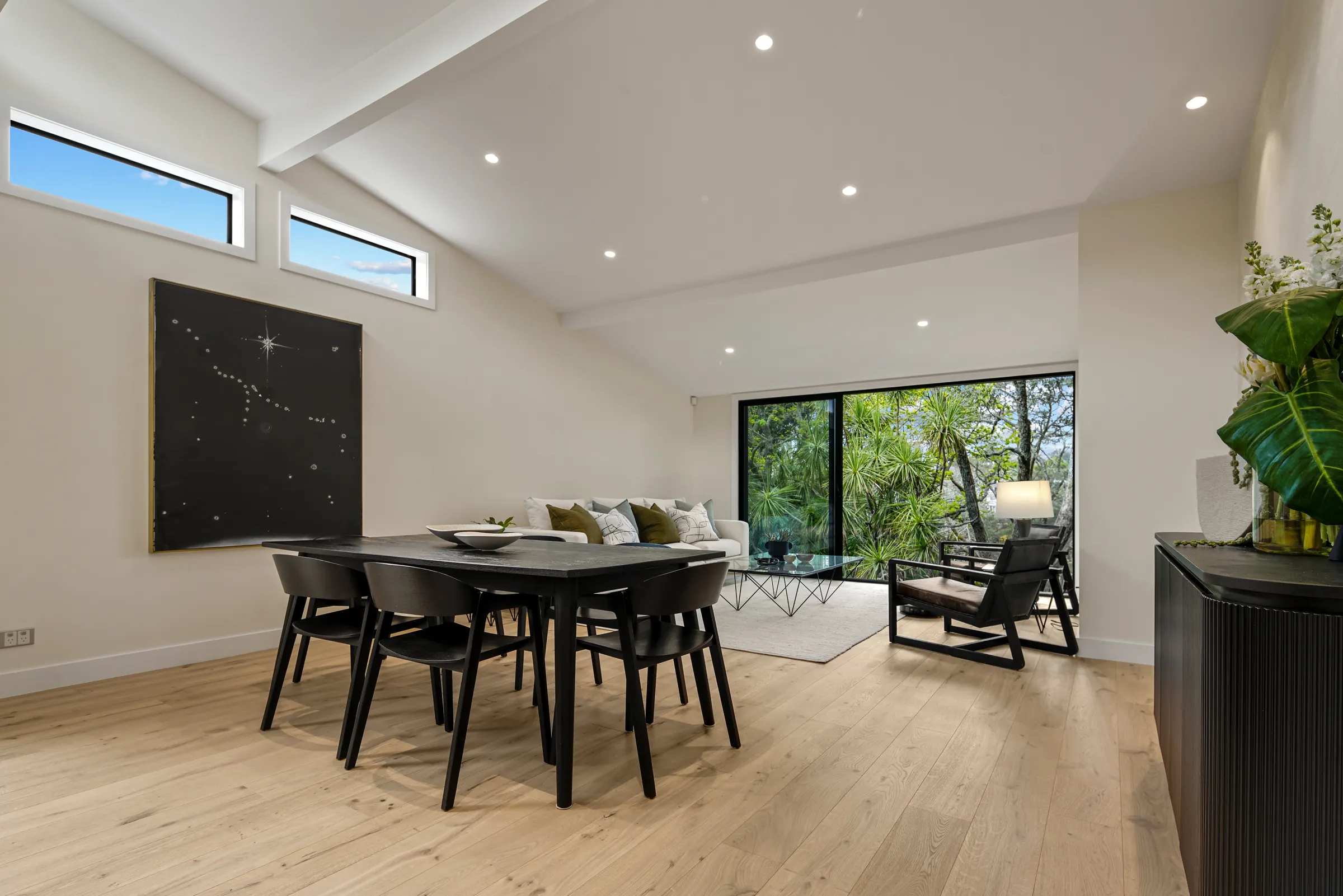 The dining table and lounge under raked ceilings on Raw 260 wide engineered timber at Seaview Road, Remuera