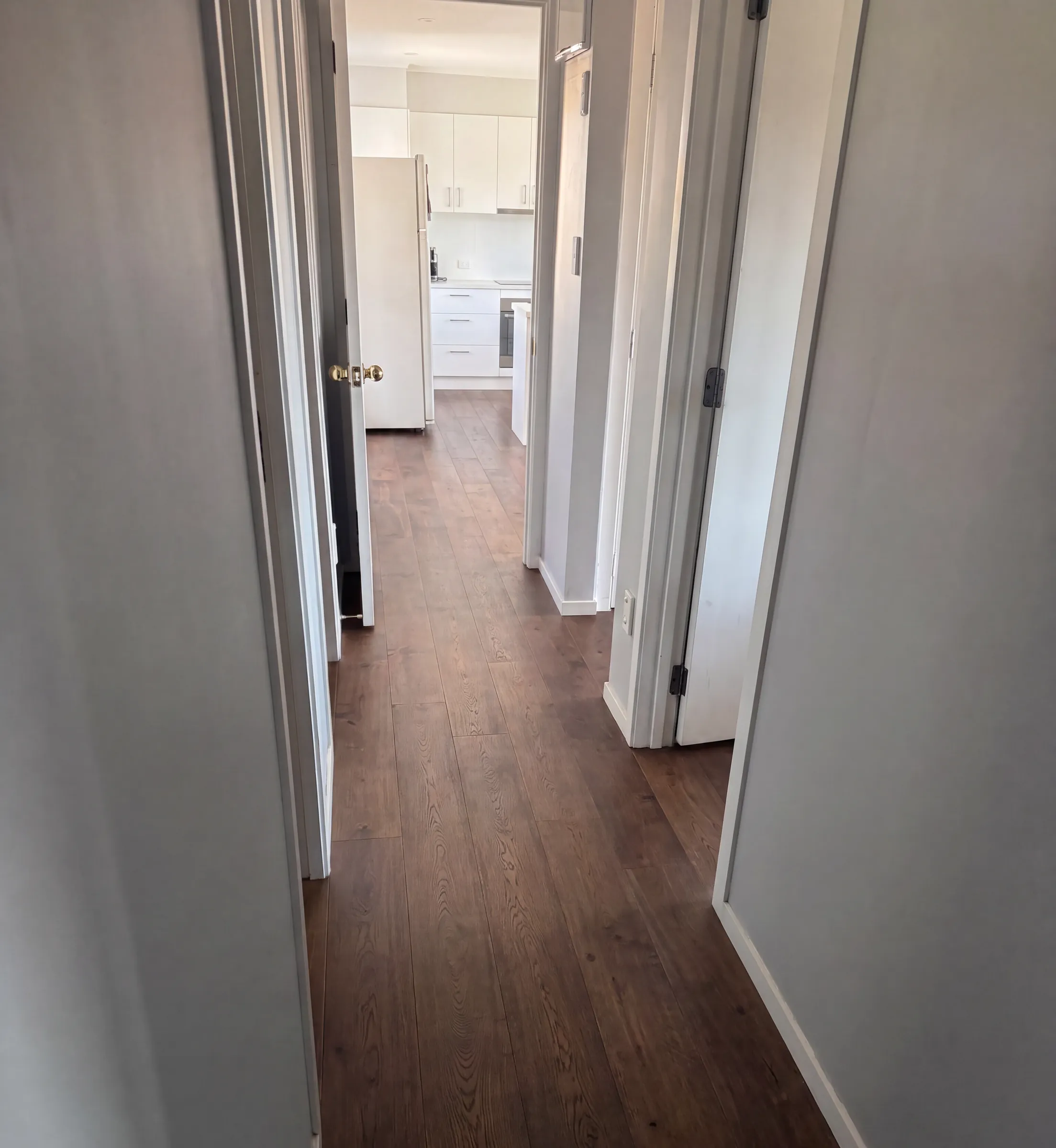 ATS Timber Walnut flooring running down a hallway into a white kitchen at Hiriri Avenue, Remuera