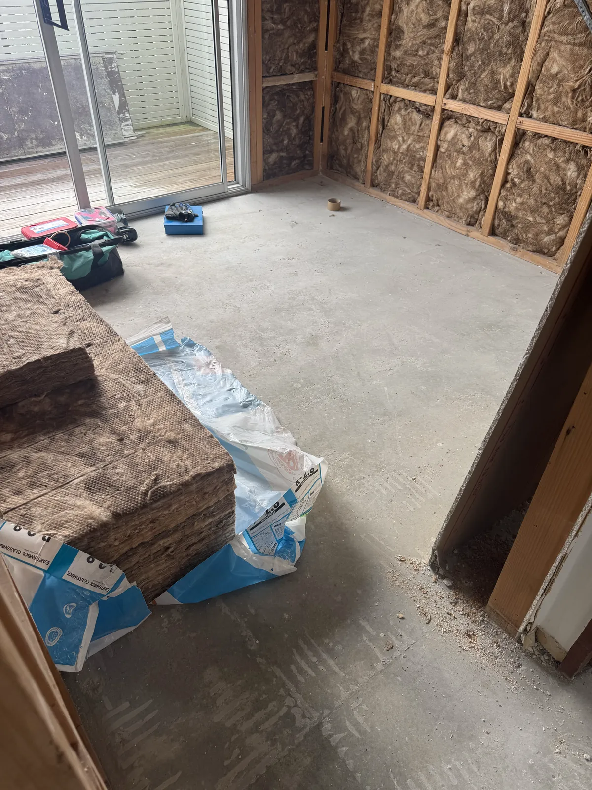A stripped room with open framing and insulation at Victoria Road, Devonport