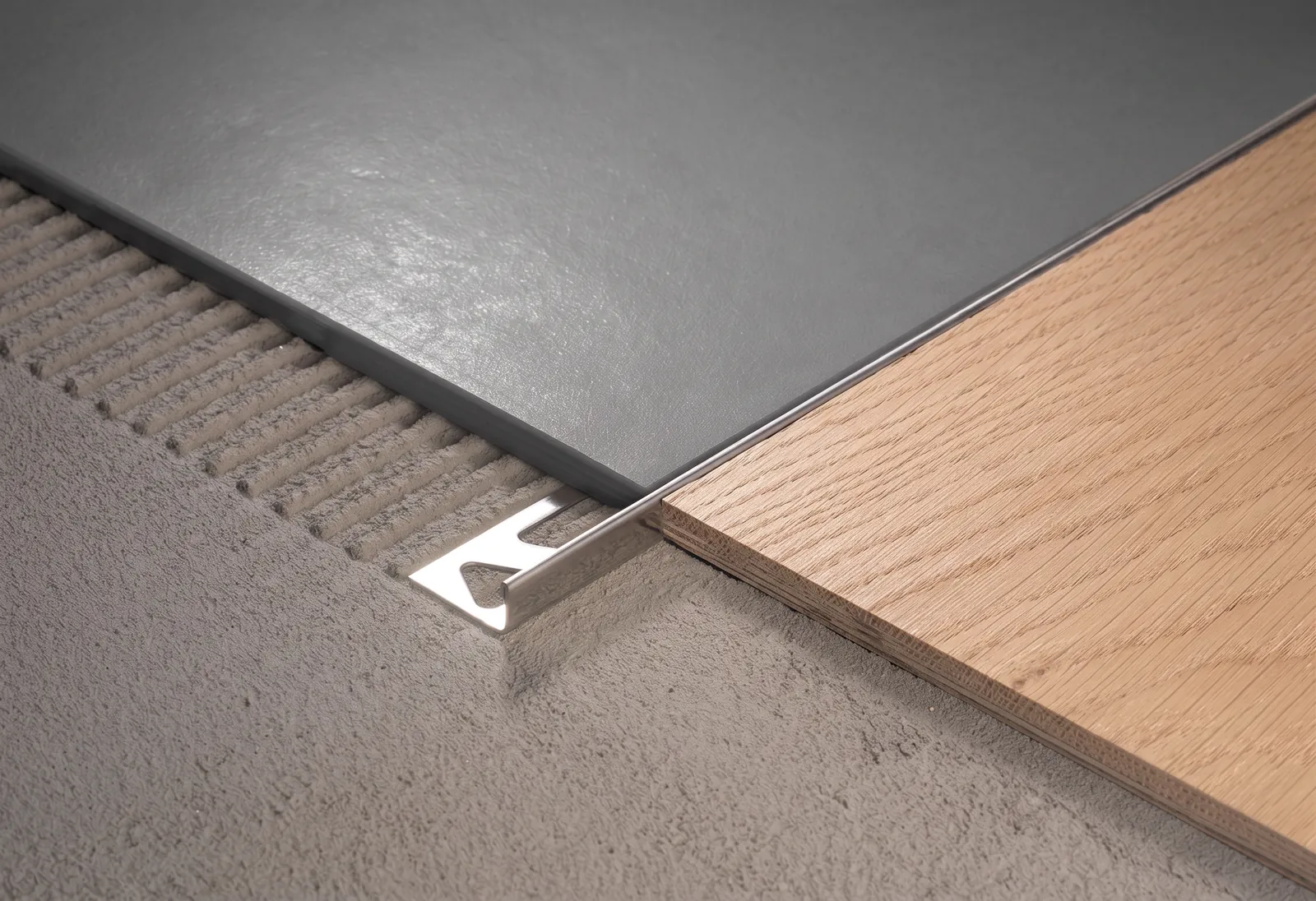 A polished silver L Channel Bar set flush into the floor where pale oak boards meet a dark grey surface