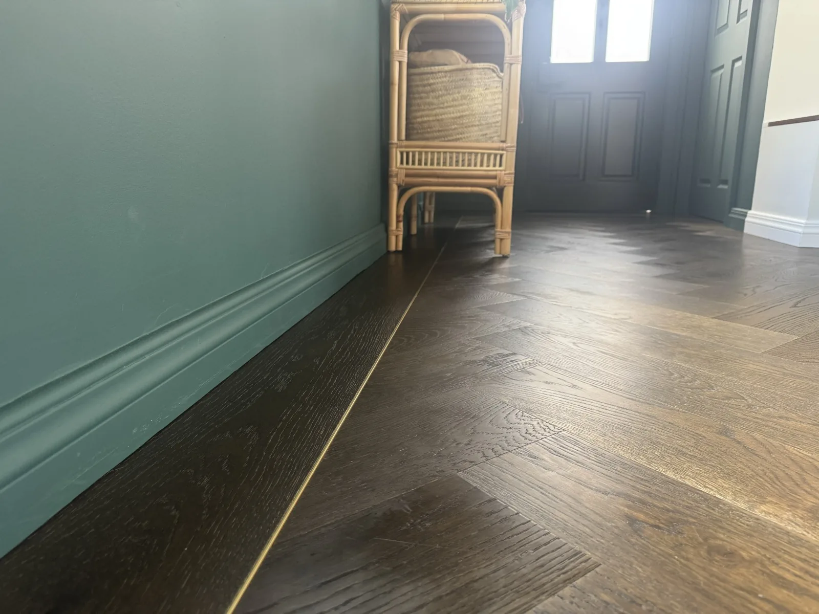 Close detail of the Slate Grey Oak Plank border and gold L Channel Bar trim framing the Herringbone field at Kitchener Road, Milford